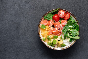 Salmon bowl with spinach, rice, avocado, tomato, cucumbers on black background, top view. Poke bowl, healthy eating