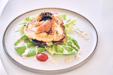 Close-up breakfast of potato pancakes with lightly salted salmon, herbs and cream sauce top view. With space to copy. High quality photo