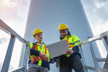 Fototapeta premium Two men wearing safety gear and holding a laptop