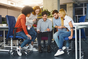 Young creative team discussing new project, working in modern coworking space