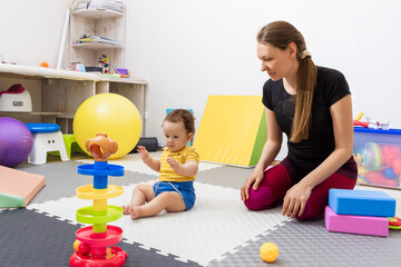 Paediatric physiotherapy treatment. Physiotherapist works with a young child on motor skills...