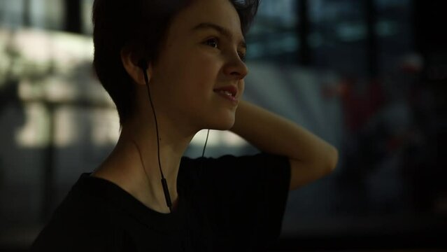 teenage girl 13 years old with short hair listens to music using headphones and walks through the shopping center
