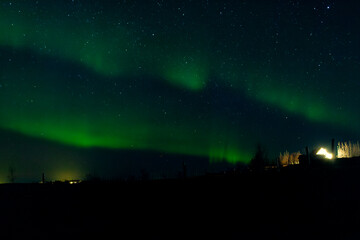 A mesmerizing view of the northern lights illuminating the night sky above a serene hill