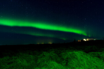 A mesmerizing view of the northern lights illuminating the night sky above a serene hill