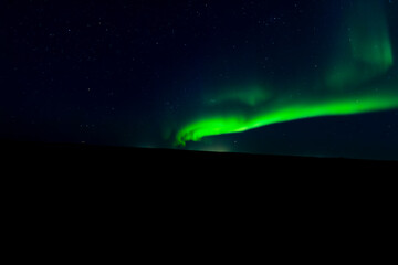 A mesmerizing view of the northern lights illuminating the night sky above a serene hill