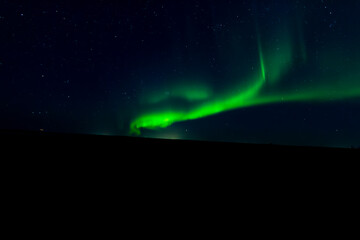 A mesmerizing view of the northern lights illuminating the night sky above a serene hill