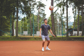Soccer player in 20s plays with a balloon on a clay court. Amateur sport. Individual football training. Soccer. Kicking, striking, passing and dribbling