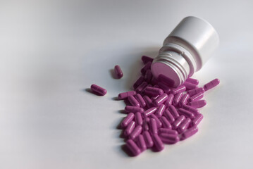 Capsula rosa esparcidas fuera de un frasco de medicina blanco,  temas de salud, belleza,...