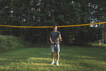 Black-haired badminton player practices his strokes on the grass court. Individual technique training. Amateur concept of the sport. The joy of the game