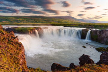Godafoss waterfall flowing with colorful sunset sky in summer at Iceland