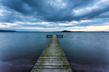 Fototapete Pier Wooden pier leading into the lake with cloudy sky in gloomy day  © Mumemories