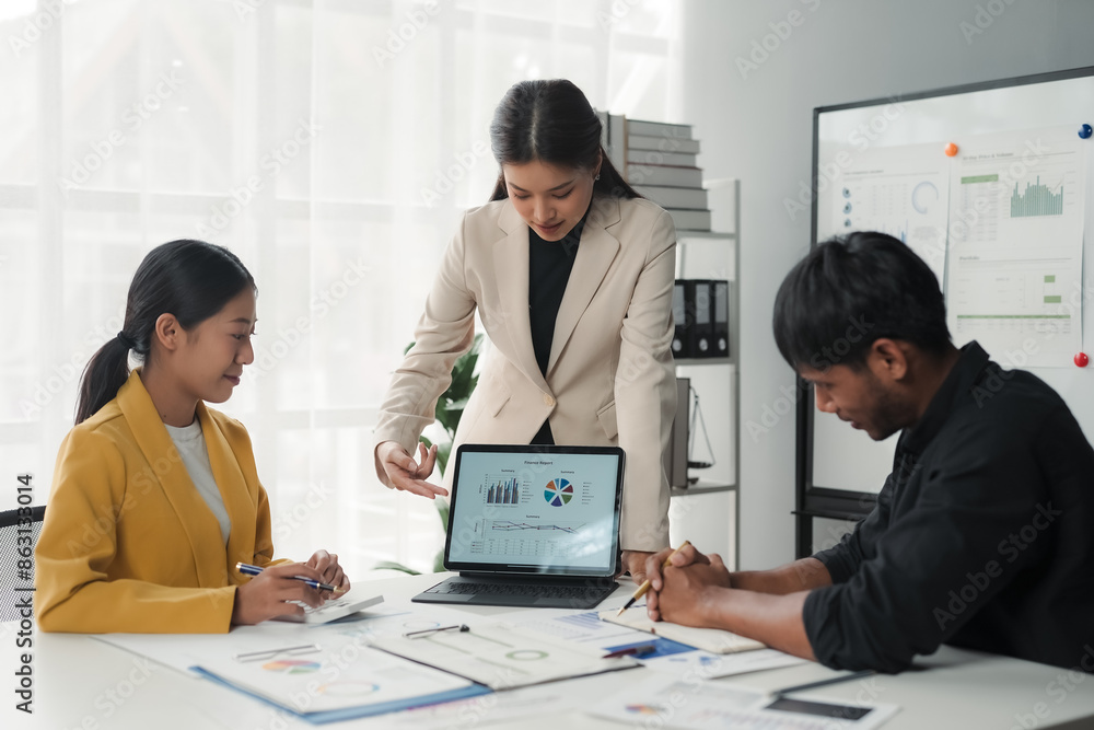 Wall mural Asian businesswoman pointing at tablet during meeting with colleagues