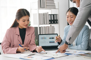 Asian business team working with financial data and using laptop