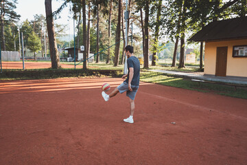 Black-haired athlete plays with a balloon on a clay court. Amateur sport. Individual football training. Soccer. Kicking, striking, passing and dribbling