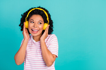 Photo of youngster girl with curly hairstyle listen music her new wireless headphones looking empty...