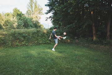 Black-haired athlete plays a friendly football match on the lawn. Amateur sport. Man playing with a ball. Dribbling practice. Sport lifestyle