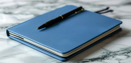 Sleek blue notebook with a black pen on a minimalist study table, welcoming students back to school after summer.
