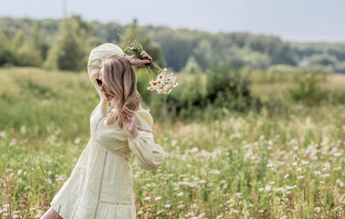Portrait of a pretty 30+ white woman in a yellow linen dress in a field with a bouquet of field...