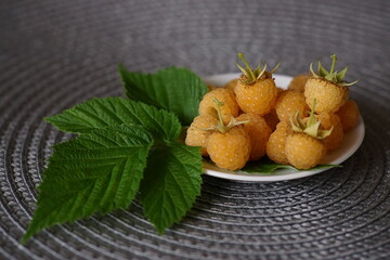 Beautiful background with yellow raspberr fruits on the plate; Rubus Idaeus Var. Luteus