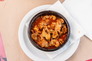 Stewed chicken gizzards in a sauce in a bowl on the table. Top view. Typical Spanish appetizer