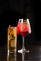 cocktail long drink glasses with whiskey and energy drink and watermelon berries and ice isolated in corner black background