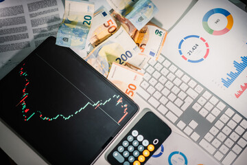Stock charts on tablet screen. Desk from above. Euro currency banknotes
