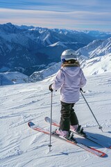 A young girl stands at the top of a snowy slope, looking out at the winter landscape