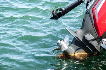 Naklejka premium Outboard engine propeller on motorboat closeup on sea waters background