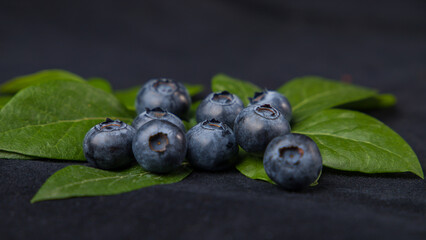 Blueberries with leaves on a black background. Shallow depth of field