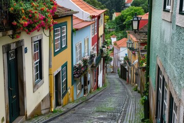 Fototapeta premium A top-down view of a narrow cobblestone street lined with colorful houses and overflowing with window flower boxes.