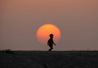 Silhouette of a child playing with sun at the backdrop, Bahrain
