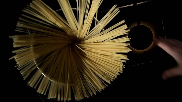 Man cooking pasta. Hand of chef throwing spaghetti into pot on kitchen stove, top view. Italian cuisine, food preparation.