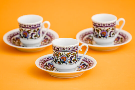 Classic porcelain Turkish coffee cups with floral design on orange background.