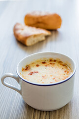 Traditional Turkish yoghurt soup served with bread, on wooden background.