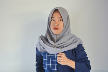 Portrait of young Asian Muslim woman with pointing gesture on white background