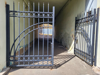 The facade of a yellow house with an arch and wrought iron gates