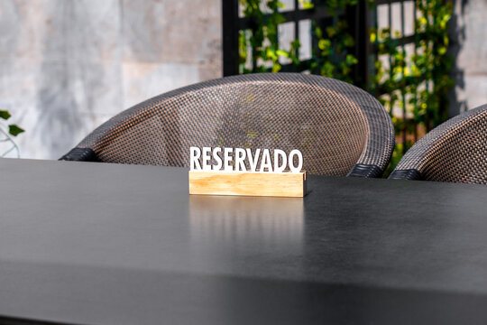 A wooden sign with the inscription RESERVADO stands on a table with two chairs