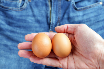 Two eggs in male hand on man jeans background. Infertility urological diseases concept