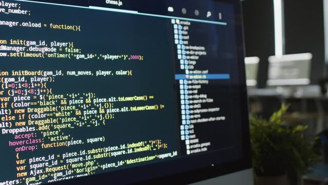 Close-up no people shot of desktop computer screen with lines of code on black background in programming language, in classroom during mobile game app development course