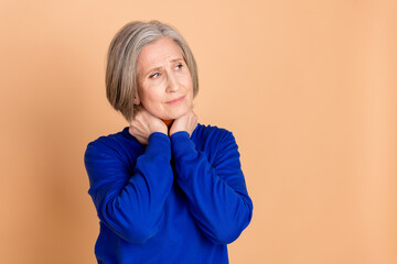 Photo portrait of attractive retired woman look empty space throat pain dressed stylish blue clothes isolated on beige color background