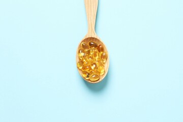 Wooden spoon of Omega-3 capsules on color background with copyspace. Healthcare, wellbeing and supplements.
