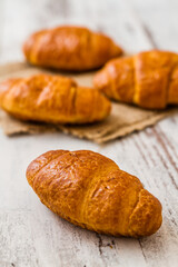 Freshly baked croissants, placed on a rustic white wooden table.