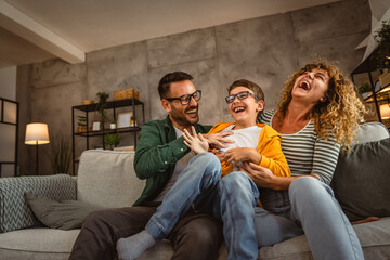 happy family of three have a fun at home tickle son and hug each other