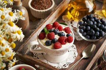 Cottage cheese mixed with flax seed oil in a bowl, with fresh raspberries and blueberries on a table