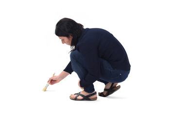 side  view of a woman squatting and painting  on the  floor on white background
