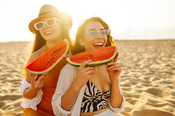 Two laughing women with watermelon on beach. Picnic. People, lifestyle, travel, nature and vacations concept.