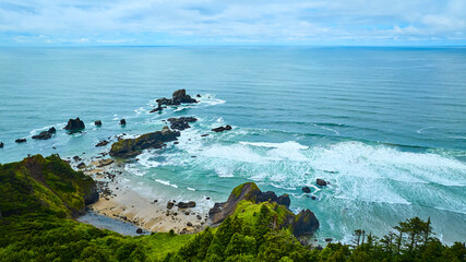 Aerial View of Rugged Coastline with Ocean Waves and Green Cliffs