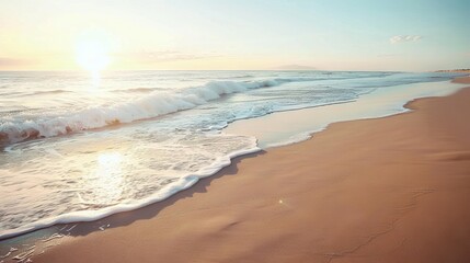 Obraz premium Soft waves gently lap at the shore of a sandy beach, illuminated by the warm glow of the setting sun.