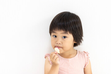 ポテトチップスを食べて舌を出す女の子（3歳、日本人、ショートヘア）