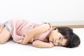 Obraz premium 絨毯に寝転がる笑顔の女の子（3歳、日本人、ショートヘア）